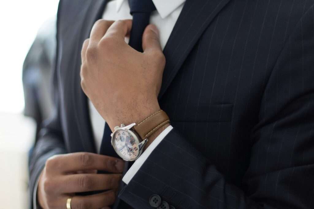 Geschäftsmann im Anzug richtet seine Krawatte – Symbol für strategische Beteiligungen