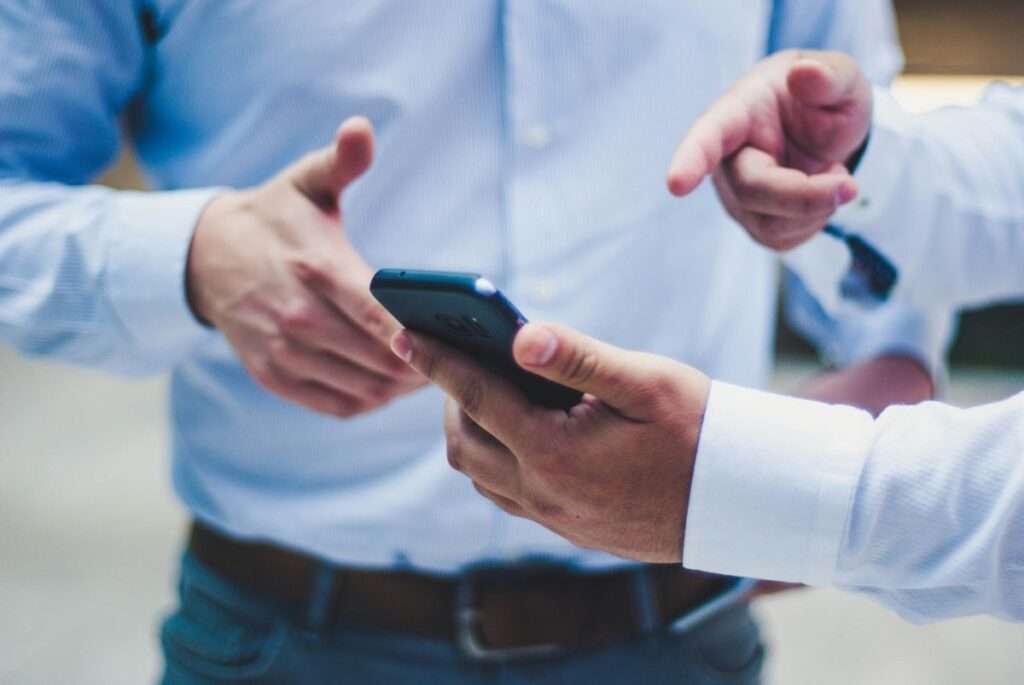 Zwei Investoren im Gespräch – Nahaufnahme mit Smartphone